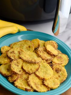 some fried food on a blue plate next to a banana and an air fryer