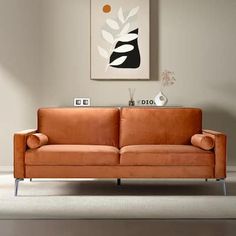 an orange couch sitting in front of a painting on the wall