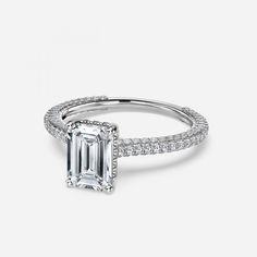 an emerald - cut diamond ring with pave set shoulders and sidestones on the band