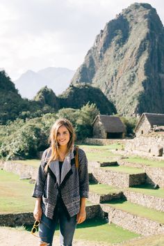 a woman is standing in front of the ruins at machu picchuta, peru