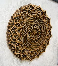 an intricately designed wooden wall hanging on the side of a white wall with a black frame