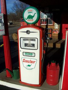 a red and white gas pump sitting on top of a sidewalk