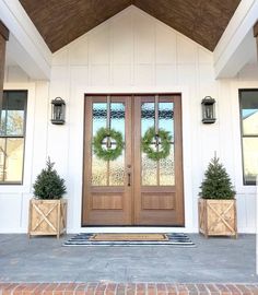 two planters with wreaths on each side of the door