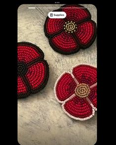 three red and white beaded brooches sitting on top of a table