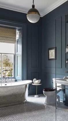 a bathroom with a tub, toilet and sink in it's blue color scheme