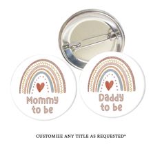 two badges with the words mommy to be and rainbows on them, one is for mom