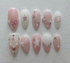 the nails are decorated with pink and white designs, including hearts, stars, and bows