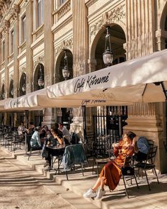 people sitting at tables in front of an old building with cafe kisini written on the awning