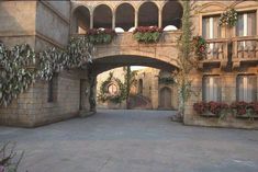 an old building with flowers growing on it's sides and arches over the entrance