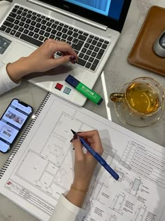 a person sitting at a desk with a laptop and pen