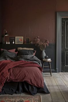 a bed sitting in a bedroom next to a wooden floor with a vase on top of it