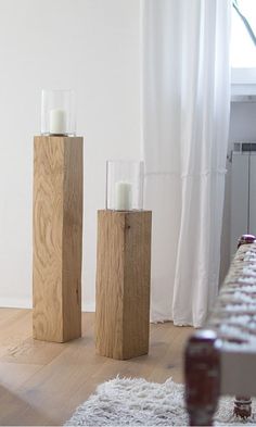 two candles are placed on wooden blocks in front of a computer keyboard and white curtains