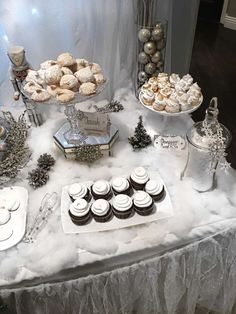 a table topped with cupcakes and pastries on top of snow covered plates