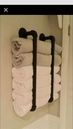 towels are hanging on the wall in a bathroom with two black towel racks and one white towel rack