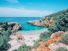 the beach is surrounded by trees and rocks