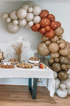 a table topped with desserts and balloons in the shape of an oatmeal arch