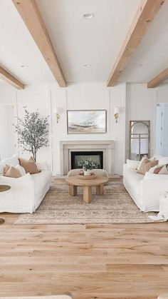 a living room filled with white couches and a fire place next to a fireplace