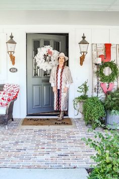 an older woman standing in front of a door with wreaths on the outside wall