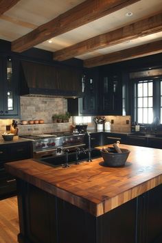 a large kitchen with black cabinets and wooden counter tops, along with an island in the middle