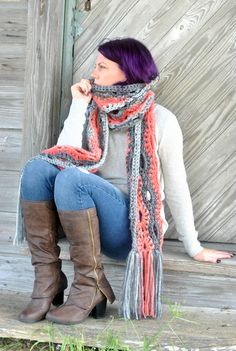 a woman sitting on a porch wearing boots and a scarf