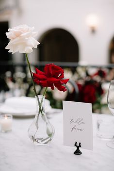 two vases with flowers in them sitting on a table next to a place card