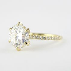 a yellow gold engagement ring with a round cut diamond and pave set diamonds on the band