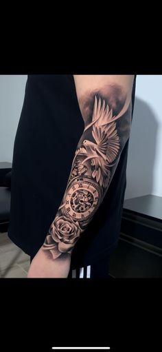 a man's arm with a clock and bird tattoo on the left arm, and roses in the middle