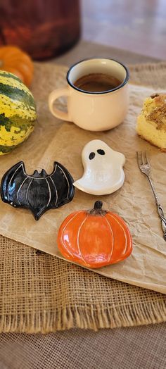 a table topped with lots of different types of halloween decorations next to a cup of coffee