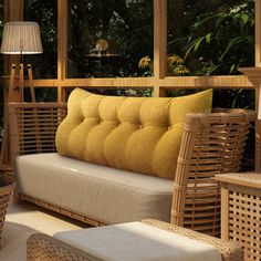 a wicker couch sitting on top of a wooden floor next to a table and chair