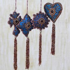 three heart shaped ornaments hanging from strings with tassels and bead work on them