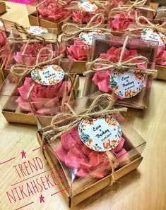 several small boxes filled with pink flowers on top of a wooden table next to each other