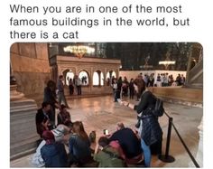 people are sitting on the ground in front of a building and one person is taking pictures