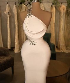 a mannequin with a white dress on display in front of other gowns