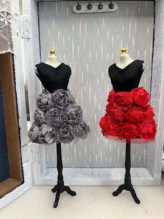 two mannequins dressed in black, red and grey dresses with roses on them