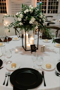 the centerpieces on this table are filled with white flowers and greenery as well as candles