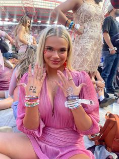 a woman in a pink dress sitting on the ground with her hands up to her face