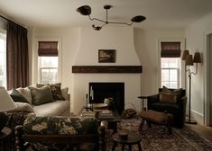 a living room with couches, chairs and a fire place in the center area