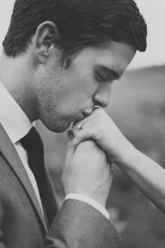 a man in a suit and tie with his hand on his chin looking down at the ground