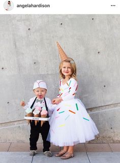 two children dressed up in costumes standing next to each other on the side of a building