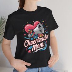 Show your school spirit with our **Cheer Mom Shirt Perfect for supporting your cheerleader, this **Cheerleader Mom Shirt** is designed for proud moms who love to cheer on their kids. This **Cheer Mom Tee** is great for game days, competitions, and school events. It makes an excellent **Cheer Mom Gift** and is a must-have addition to any cheer mom's wardrobe. Whether you're in the stands or on the go, this **School Spirit Tshirt** will showcase your pride and enthusiasm. Our **Cheer Spirit Wear** is made with comfort and style in mind, ensuring you look great while rooting for your team. Get ready to shine with this versatile **Cheer Tee **Product Details - 100% Airlume combed and ringspun cotton (fiber content may vary for different colors) - Light fabric (4.2 oz/yd² (142 g/m - Retail fit Graphic Tee T-shirt For Cheerleading, Black Sublimation Print T-shirt For Cheerleading, Black T-shirt With Sublimation Print For Cheerleading, Cheerleading Fan Apparel Tops With Sublimation Print, Cheerleading Graphic Print Fan Apparel Tops, Crew Neck T-shirt With Sublimation Print For Cheerleading, Team Spirit Tops With Sublimation Print For Cheerleading, Cheerleading Crew Neck T-shirt With Sublimation Print, Sports Fan T-shirt With Team Name For Cheerleading