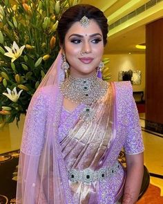 a woman in a purple sari with jewelry on her neck and shoulders, posing for the camera