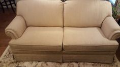 a tan couch sitting on top of a rug