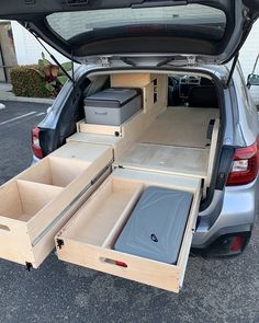 the back end of a car with its trunk open and two drawers in front of it