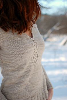 a woman standing in the snow wearing a sweater