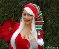 a woman with long white hair wearing a santa hat and holding a christmas ornament