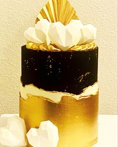 a gold and black cake with white frosting on the top is sitting on a table