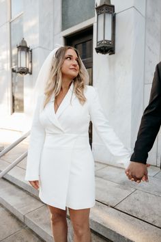 a bride and groom hold hands as they walk down the steps