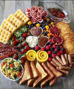 a platter with waffles, fruit, and other foods arranged in the shape of a circle