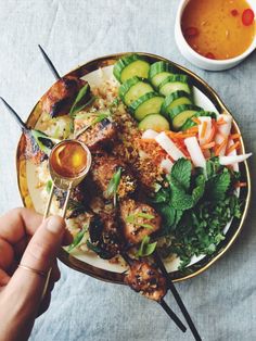 a person is holding a fork over a plate of food with vegetables and meat on it