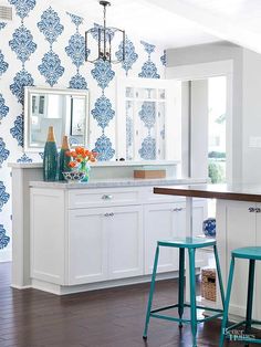 a kitchen with blue and white wallpaper, stools and a bar in the center